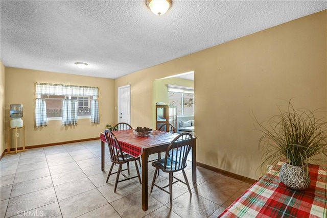 dining space with light tile patterned flooring, a textured ceiling, and baseboards