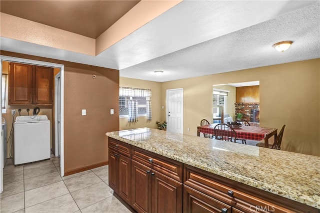 kitchen featuring light stone countertops, a textured ceiling, washing machine and clothes dryer, and light tile patterned floors