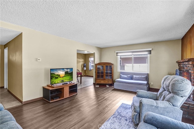 living area featuring a textured ceiling, wood finished floors, and baseboards