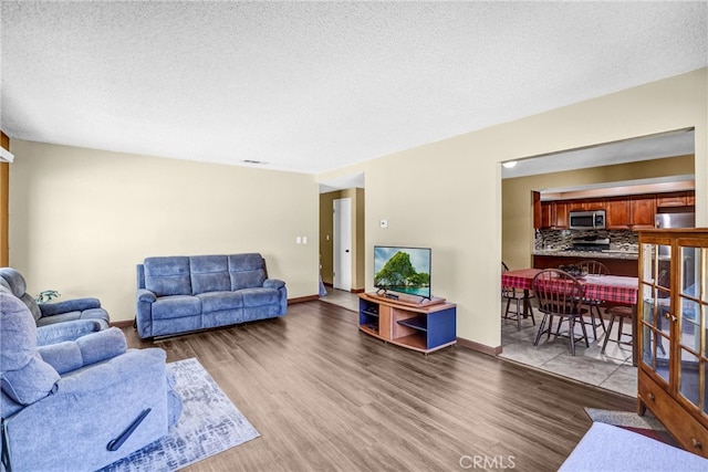 living room featuring a textured ceiling, baseboards, and wood finished floors