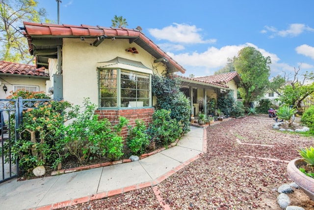 exterior space featuring brick siding, a tile roof, and stucco siding