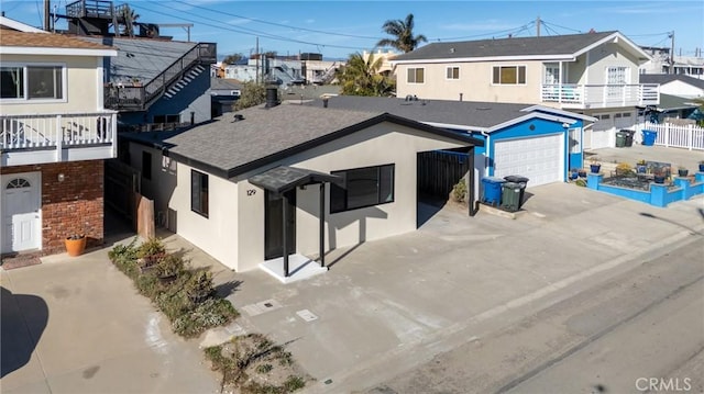 view of front of house featuring a garage, driveway, roof with shingles, fence, and stucco siding