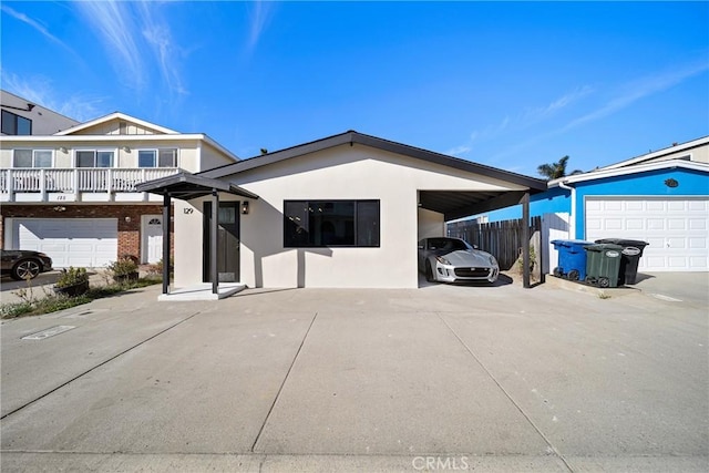 view of front facade with a carport, fence, and stucco siding