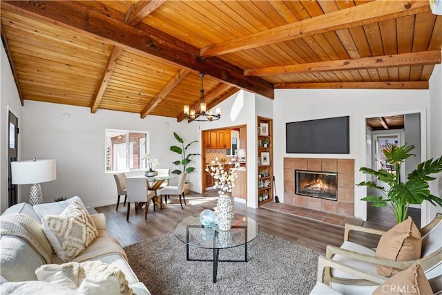 living room featuring a fireplace, vaulted ceiling with beams, a notable chandelier, and wood finished floors