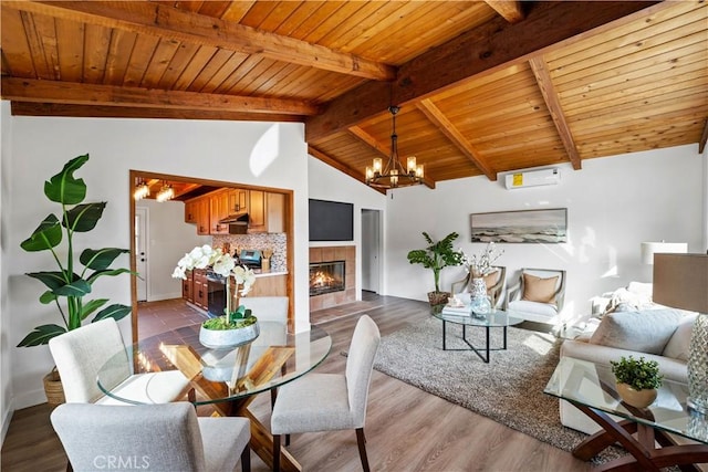 dining space with lofted ceiling with beams, wood ceiling, wood finished floors, and a tile fireplace