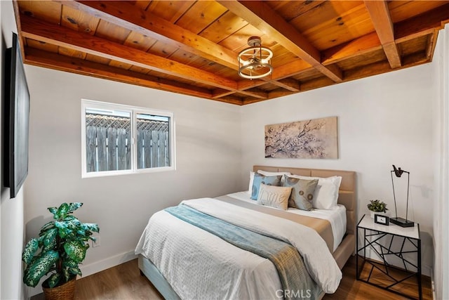 bedroom featuring beamed ceiling, wooden ceiling, wood finished floors, and baseboards