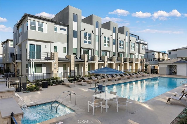 community pool with a patio, fence, and a residential view