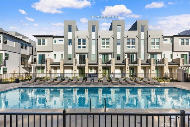 pool with a residential view, fence, and a patio