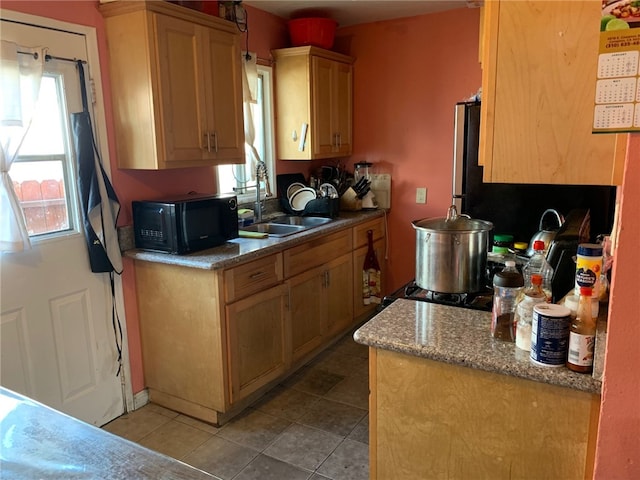 kitchen featuring black microwave, a sink, and light tile patterned flooring