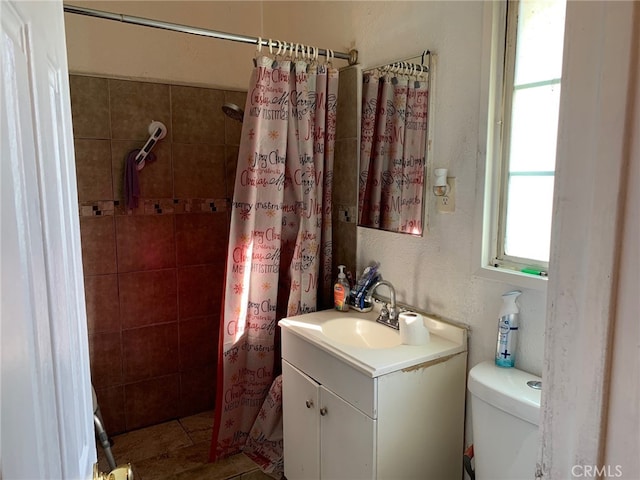 full bathroom with toilet, tiled shower, and vanity