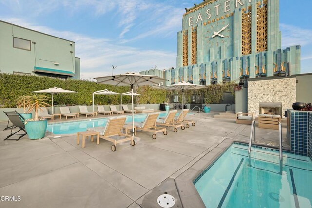 pool with exterior fireplace and a patio area