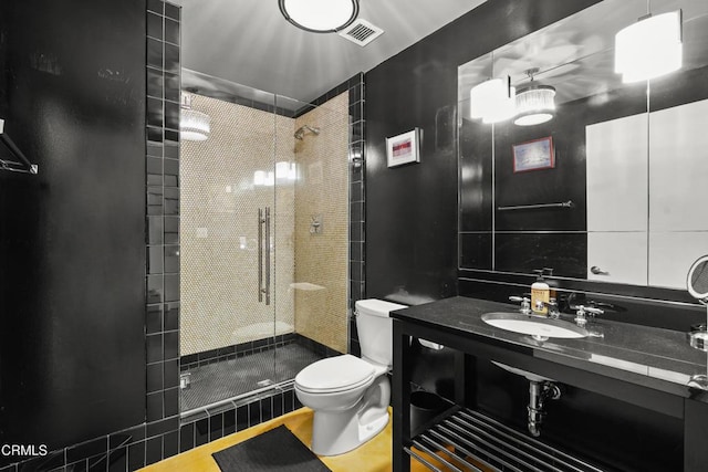 full bathroom featuring toilet, a sink, a shower stall, and visible vents
