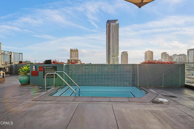 view of pool featuring a tennis court, fence, and a city view