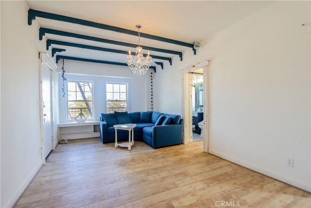 sitting room with a chandelier, light wood-type flooring, beam ceiling, and baseboards