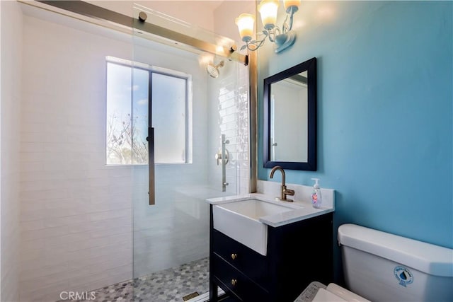 bathroom featuring a chandelier, vanity, toilet, and a walk in shower