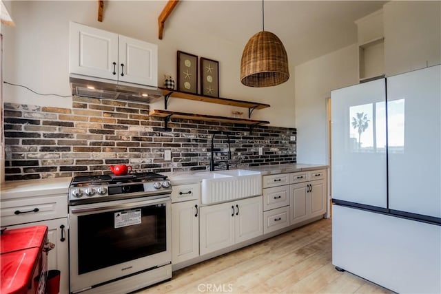 kitchen with a sink, white cabinetry, light countertops, freestanding refrigerator, and gas stove