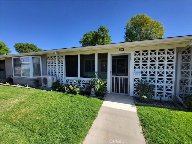 view of front of property with ac unit, a sunroom, and a front yard