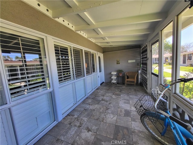 unfurnished sunroom with beam ceiling