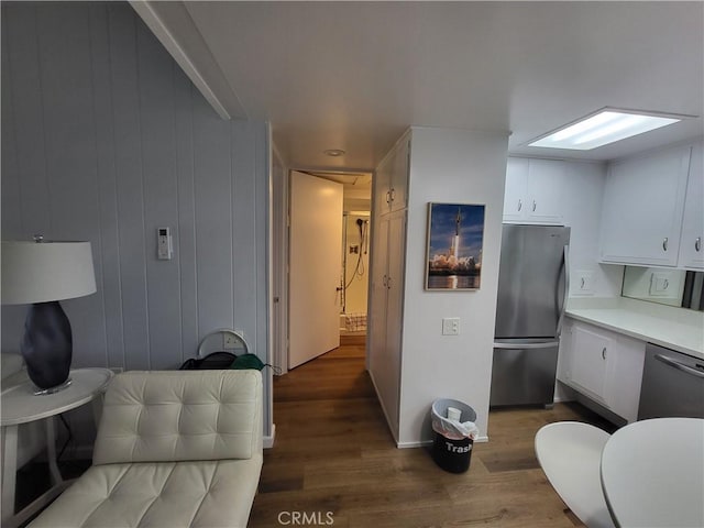 kitchen featuring white cabinets, stainless steel appliances, light countertops, and wood finished floors