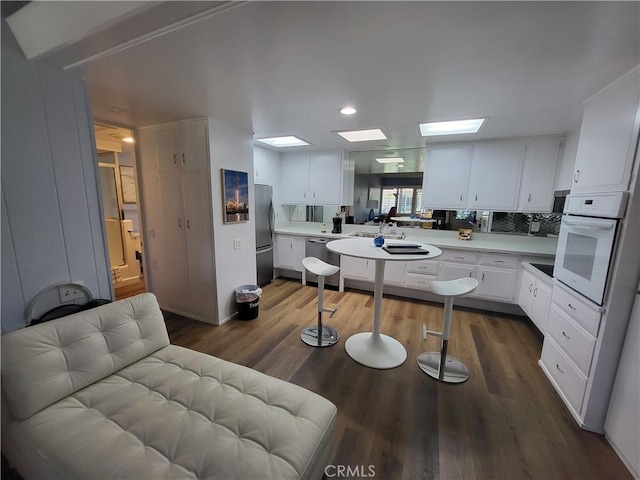 kitchen with white cabinetry, appliances with stainless steel finishes, light countertops, and dark wood finished floors