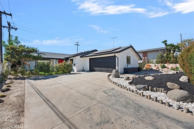 ranch-style home with roof mounted solar panels, driveway, and an attached garage