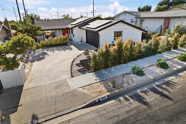 single story home featuring solar panels, driveway, an attached garage, and fence