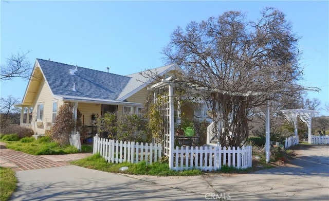 view of front of home featuring a fenced front yard, a shingled roof, and a pergola