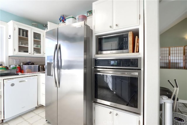 kitchen with light countertops, decorative backsplash, appliances with stainless steel finishes, glass insert cabinets, and white cabinets