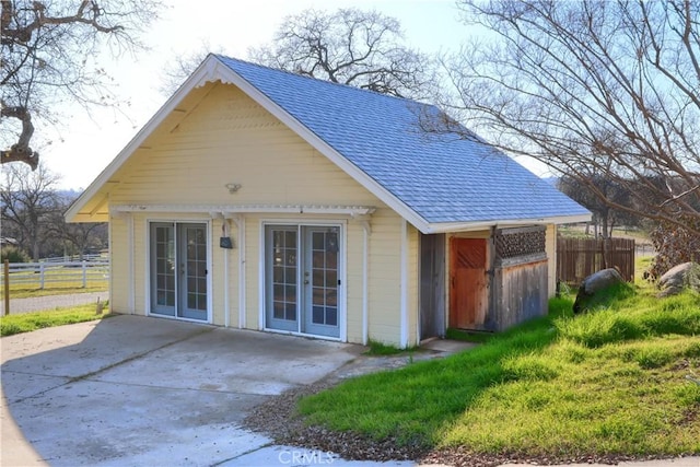 view of front of property featuring roof with shingles, fence, and french doors