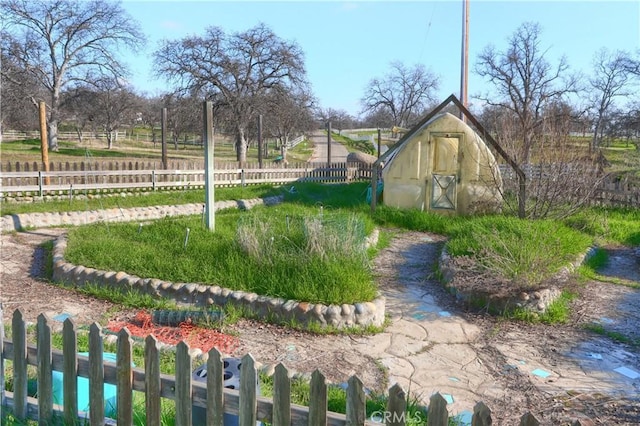 view of yard featuring a greenhouse, fence, and an outdoor structure