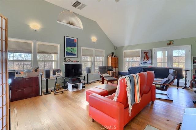 living area with french doors, visible vents, plenty of natural light, and wood finished floors