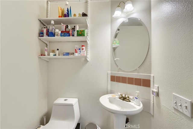 bathroom featuring decorative backsplash, a sink, and toilet