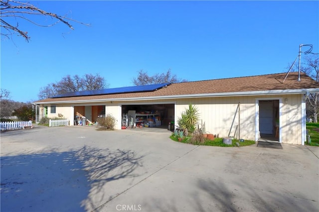 view of front of house featuring a garage, driveway, and roof mounted solar panels