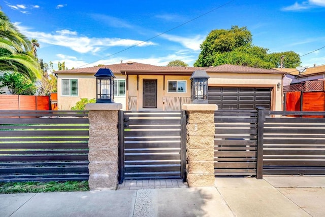 view of front of house featuring a fenced front yard, stucco siding, a garage, and a gate