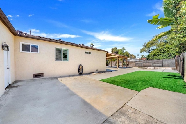 rear view of house with stucco siding, a fenced backyard, a yard, crawl space, and a patio area