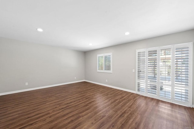 empty room with dark wood-type flooring, recessed lighting, and baseboards