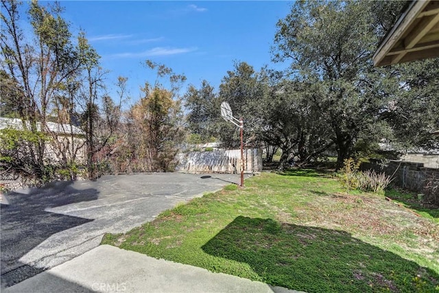 view of yard with basketball hoop and fence