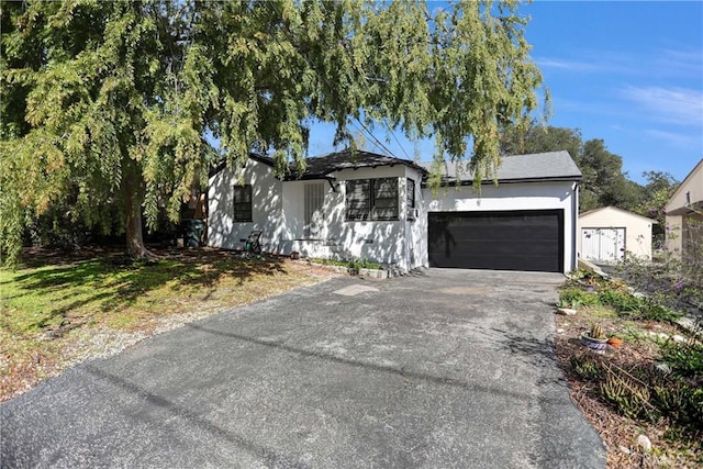 single story home featuring driveway, an attached garage, and stucco siding