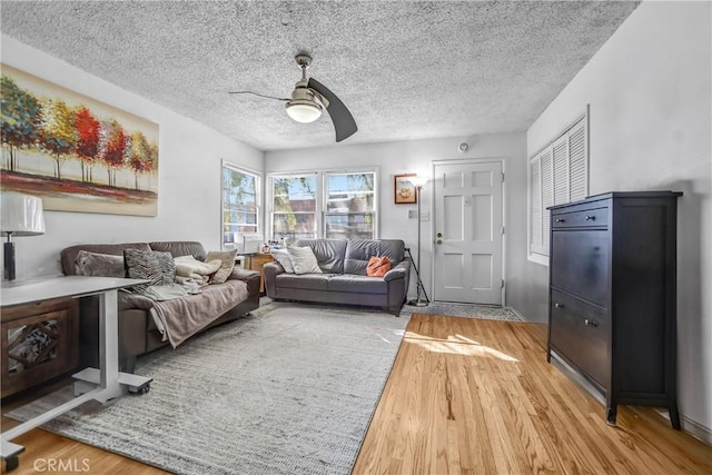 living room with light wood-style flooring, a textured ceiling, and a ceiling fan