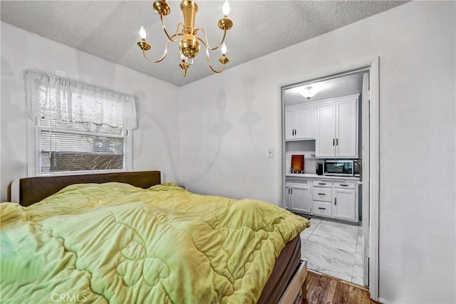 bedroom featuring marble finish floor, a textured ceiling, and a notable chandelier