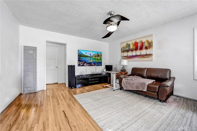 living area featuring ceiling fan, a textured ceiling, and wood finished floors