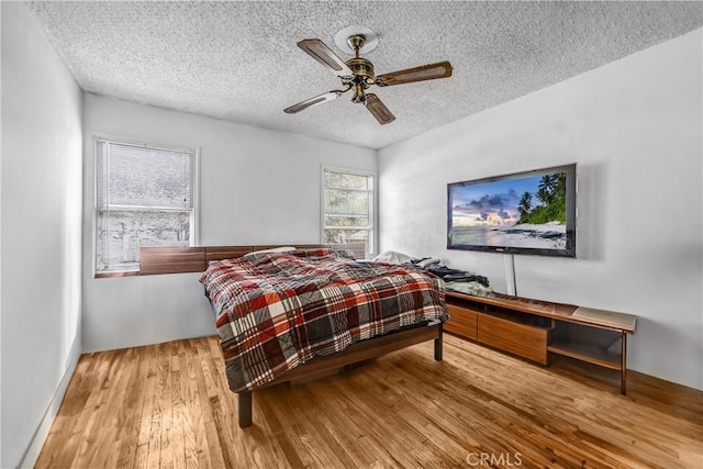 bedroom featuring ceiling fan, a textured ceiling, and wood finished floors