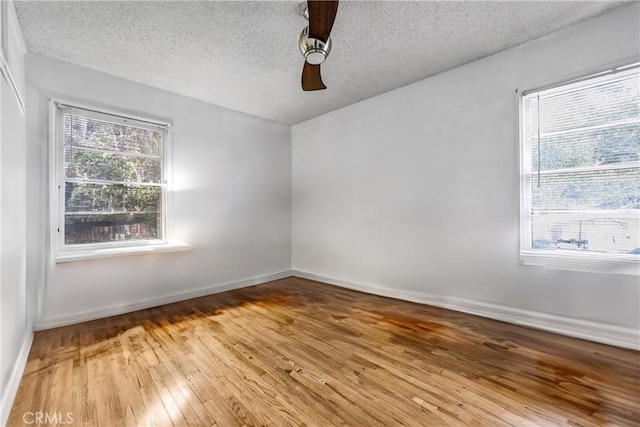 empty room featuring baseboards, a textured ceiling, and hardwood / wood-style floors