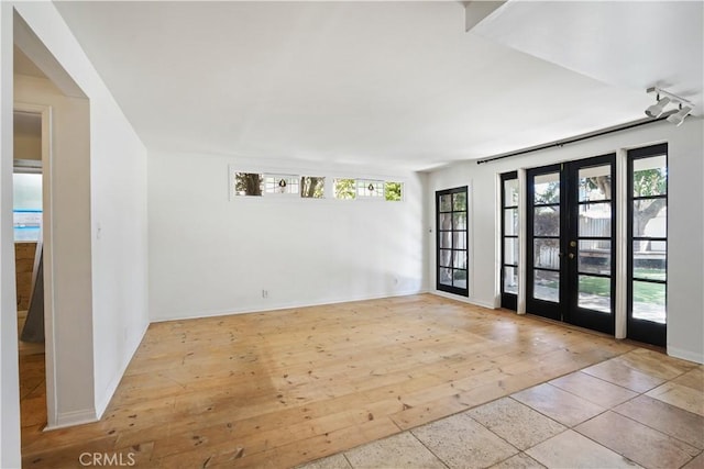 unfurnished room featuring hardwood / wood-style floors, french doors, and baseboards