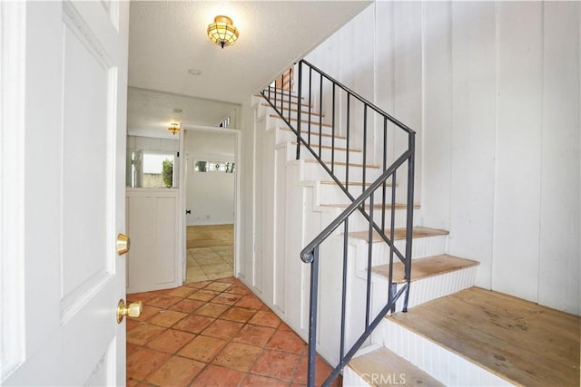 stairs with tile patterned floors and a textured ceiling