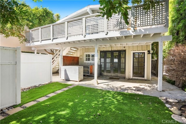 back of property with a patio, fence, a yard, french doors, and board and batten siding