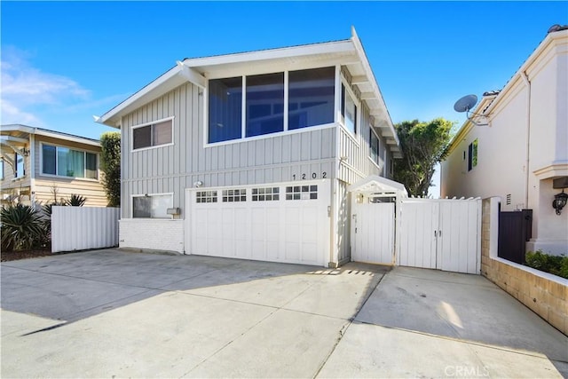 view of front of home featuring a gate, concrete driveway, a garage, board and batten siding, and brick siding