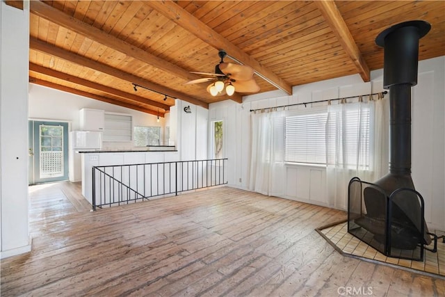 unfurnished living room with a ceiling fan, wooden ceiling, a wood stove, and light wood finished floors