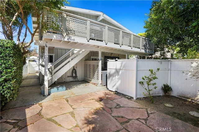 rear view of property with a patio area, stairway, fence, and board and batten siding