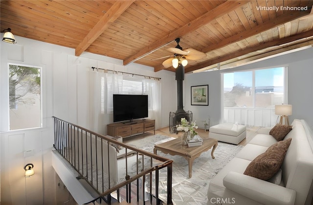 living room with beam ceiling, plenty of natural light, wood ceiling, and a wood stove